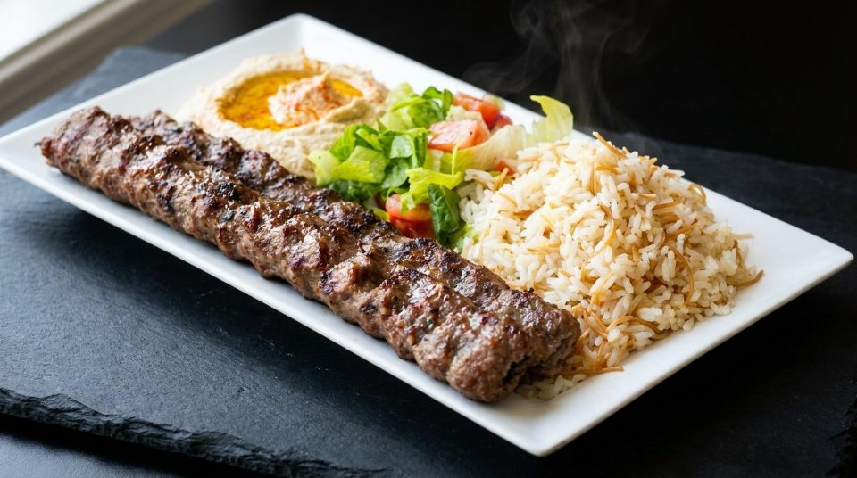 Two beef lule skewers with rice pilaf, salad and hummus